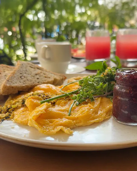 Huevos revueltos con pan de masa madre, jugos y café en la terraza