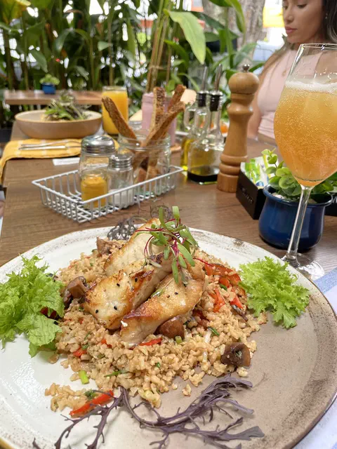 Pescado sobre arroz salteado con ensalada y jugo
