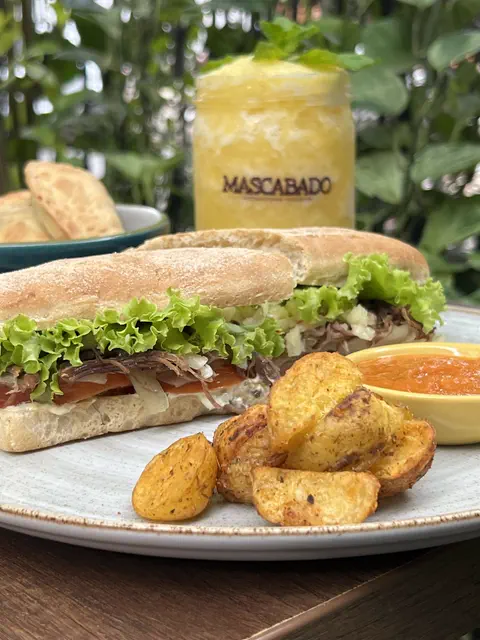Sándwich en pan de la casa con papas horneadas y jugo de mango